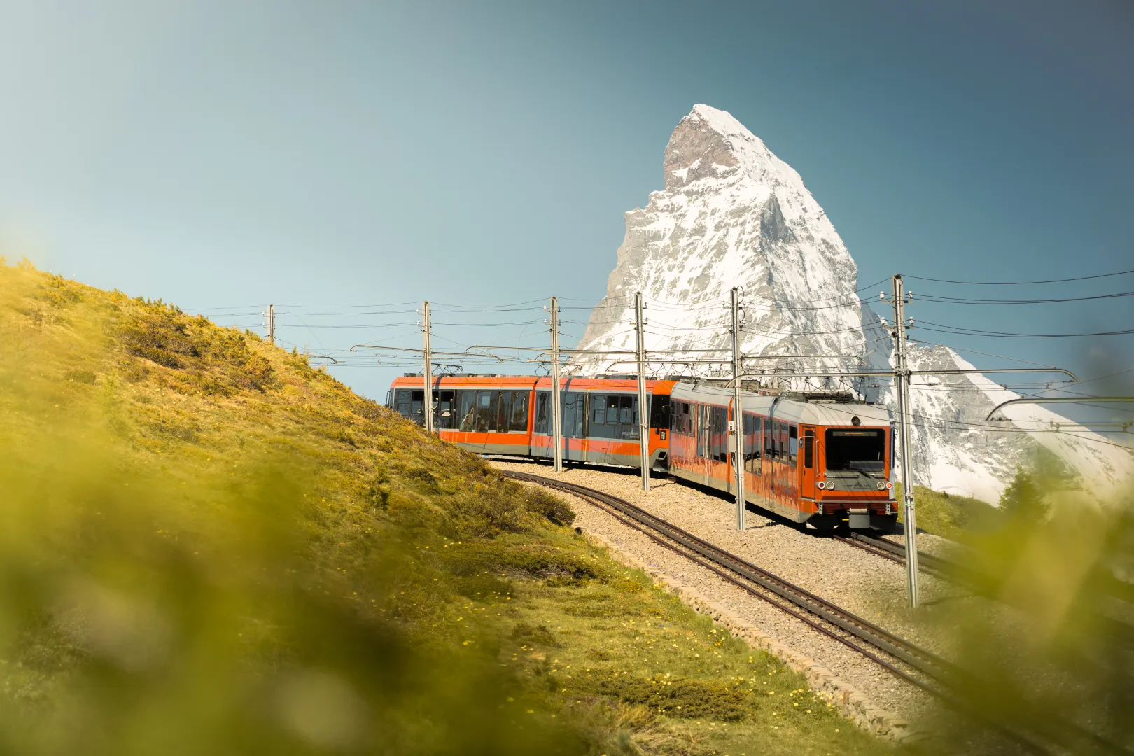 Le train du Gornergrat traverse un paysage alpin verdoyant avec vue sur le Cervin.